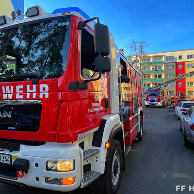 Löschfahrzeug und Drehleiter an Mehrfamilienhaus