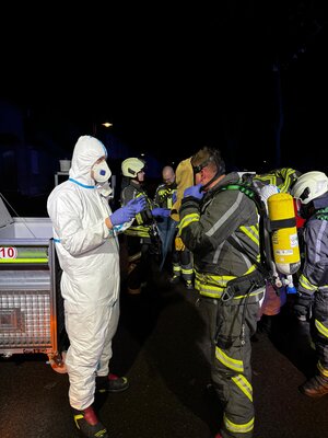 Bild vergr&ouml;&szlig;ern: Zwei Feuerwehrleute im Vordergrund in Vollschutzkleidung und Atemschutzgeräten bei nächtlichem Einsatz bei einem Garagenbrand in der Heimstätten Siedlung. Im Hintergrund sind weitere Feuerwehrleute zu sehen.