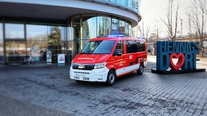 Bild vergr&ouml;&szlig;ern: Roter Mannschaftswagen der Feuerwehr mit Blaulicht vor dem Rathaus Hennigsdorf neben dem i-love-Hennigsdorf-Photopoint