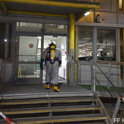 Bild vergr&ouml;&szlig;ern: Einsatzkraft der Feuerwehr mit Schutzanzug betritt Gebäude an Einsatzstelle